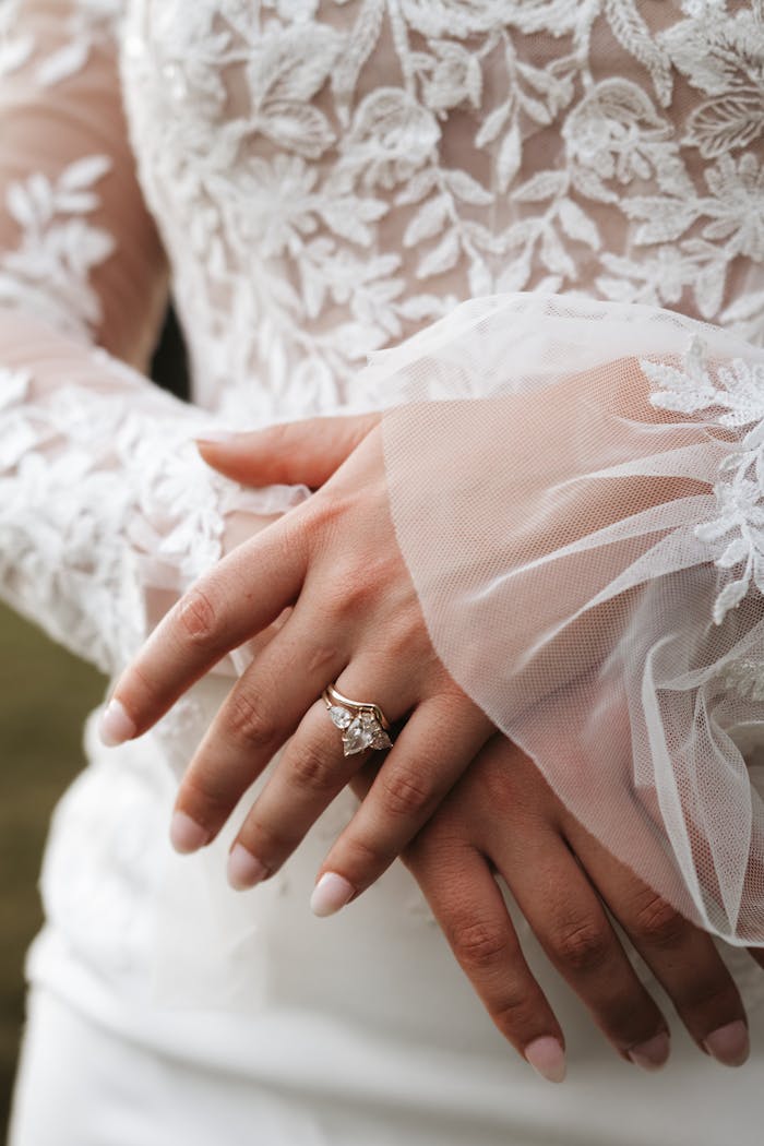 Close-up of a brides hands with lace dress and elegant ring, capturing a timeless wedding moment.